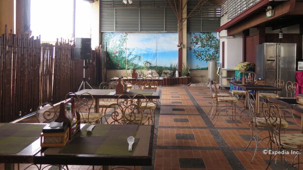 A restaurant with high ceilings, metal beams, and a mural of a tropical scene. Tables and chairs are arranged for dining.