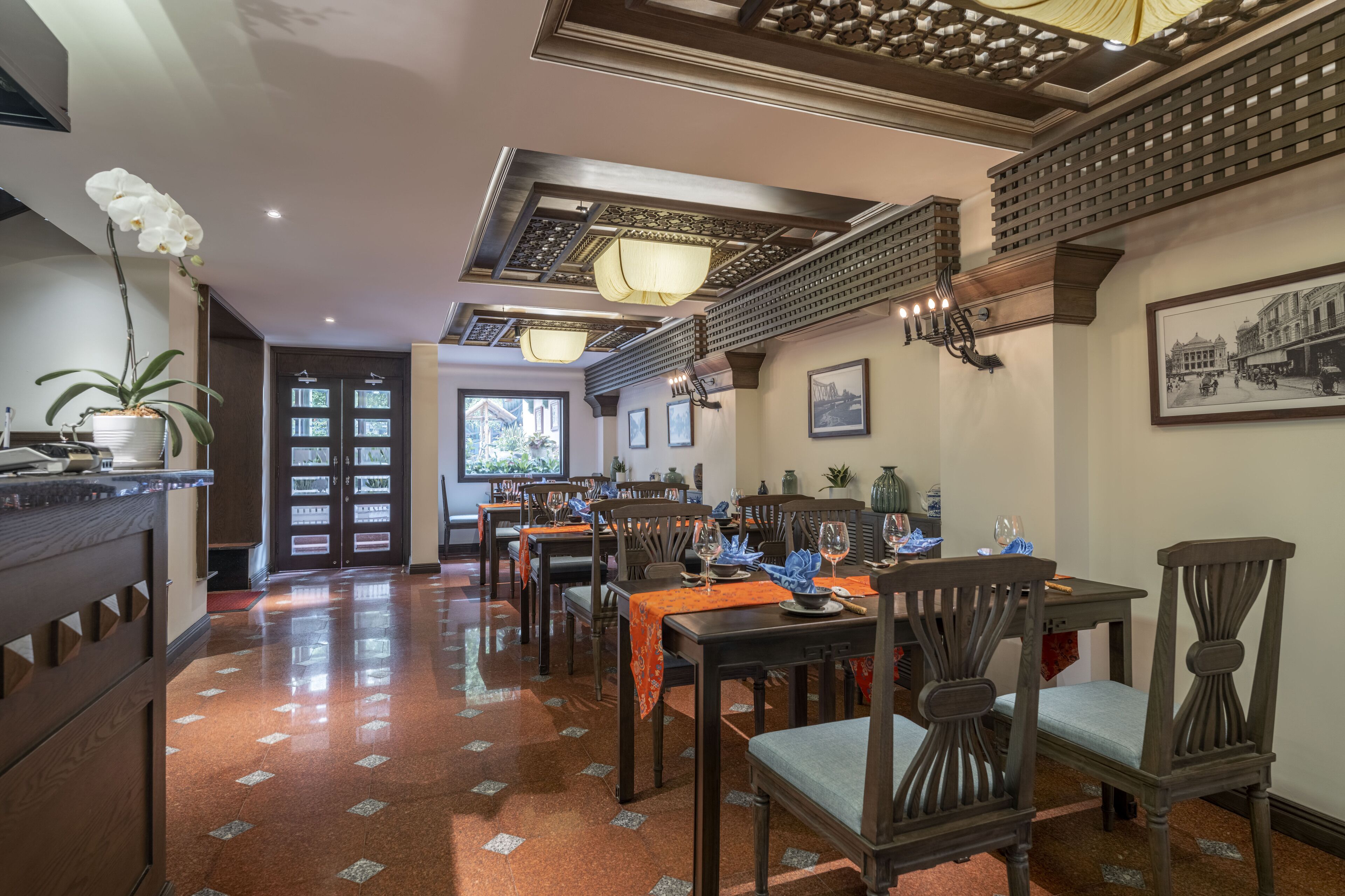 A dining area with wooden tables and chairs, a chandelier, and a view of the outside.