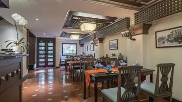 A dining area with wooden tables and chairs, a chandelier, and a view of the outside.