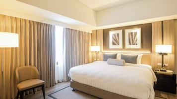 A hotel room with a large bed, a chair, a nightstand, and two wall-mounted lamps.