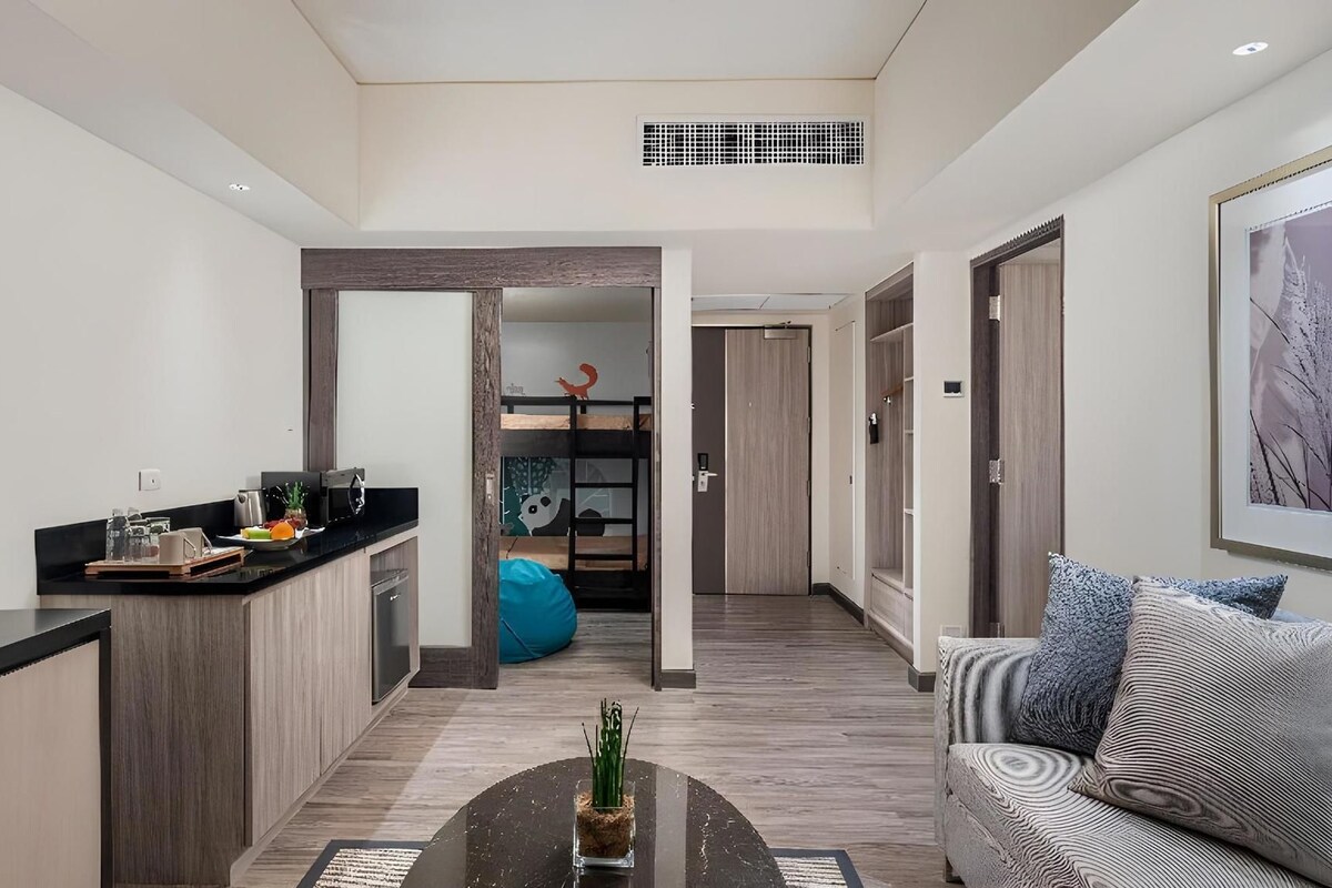 Una sala de estar moderna con un sofá, una mesa de centro y una zona de cocina con mostrador y armarios.