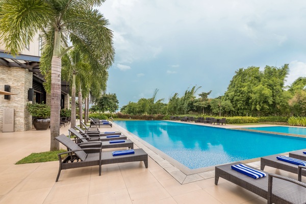 Una piscina al aire libre, sombrillas, sillones reclinables de piscina