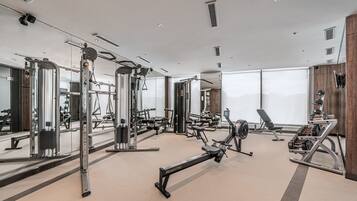 A modern gym with various exercise equipment, large windows, and a clean, spacious layout.