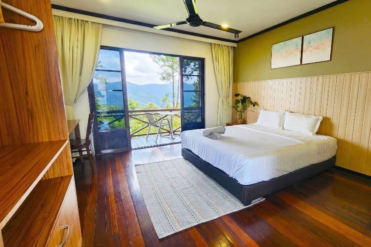 Un dormitorio con cama, suelo de madera, balcón con vistas y ventilador de techo.