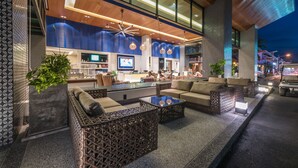 A modern hotel lobby with a seating area, a reception desk, and a large TV screen. - The Beach Heights Resort (Karon)