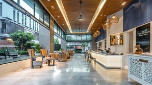 A spacious lobby with a reception desk, seating area, and large windows offering views of the outside. - The Beach Heights Resort (Karon)