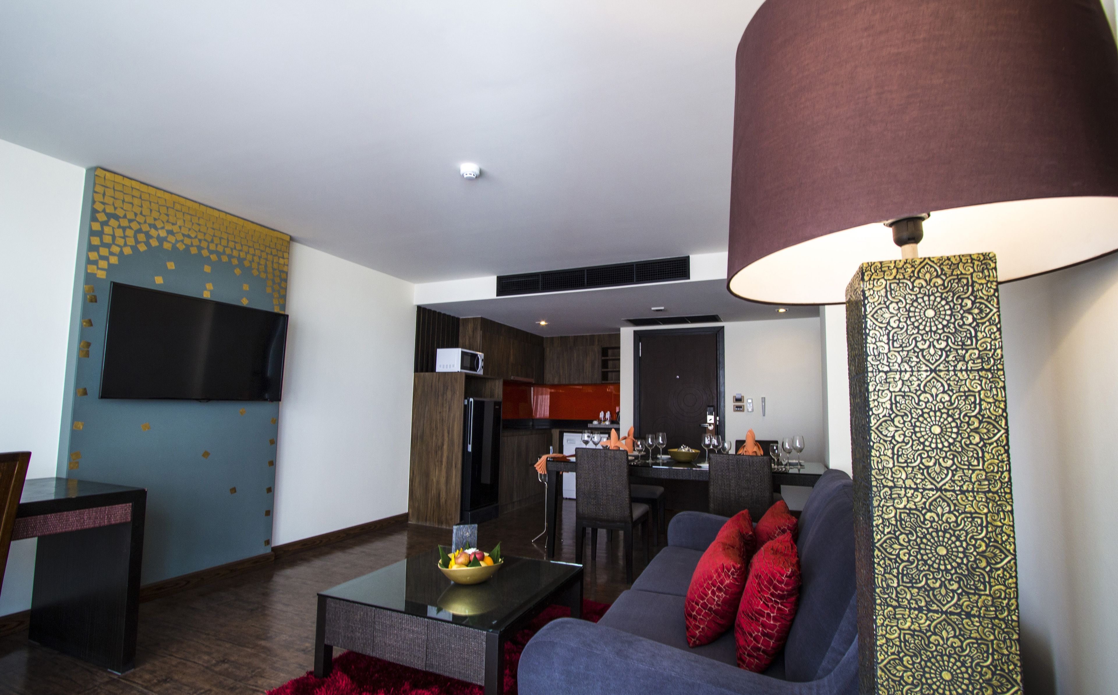 Una sala de estar moderna con un sofá, una mesa de centro con fruta, un televisor y un comedor con sillas y una mesa.