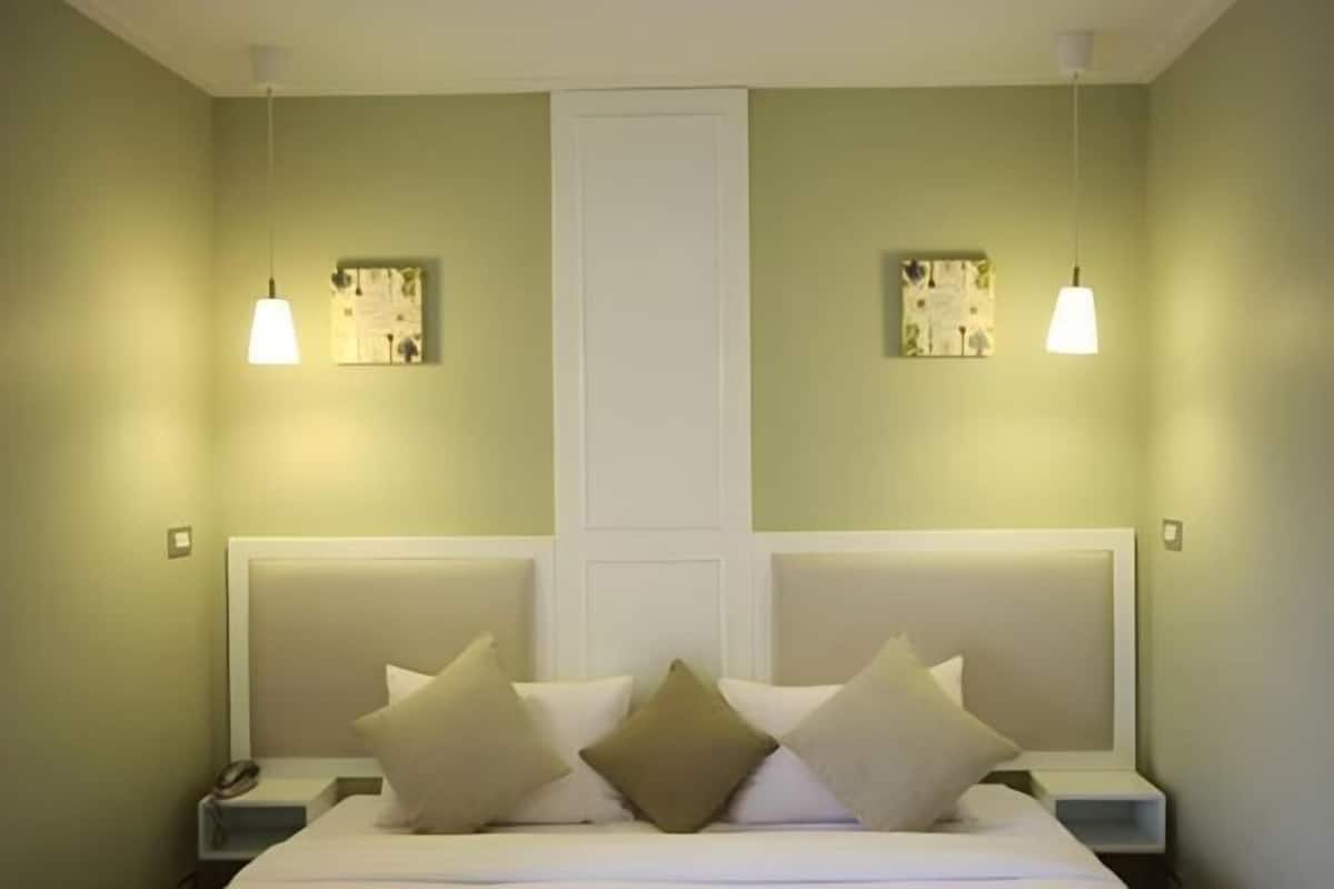 A hotel room with a bed, bedside tables, and two wall-mounted light fixtures.