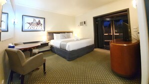 Habitación de hotel con cama, escritorio, silla, televisor y un cuadro en la pared.