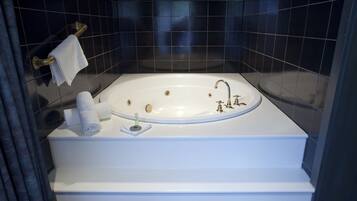 Un baño moderno con una bañera independiente, un perchero y un estante pequeño con artículos de aseo.