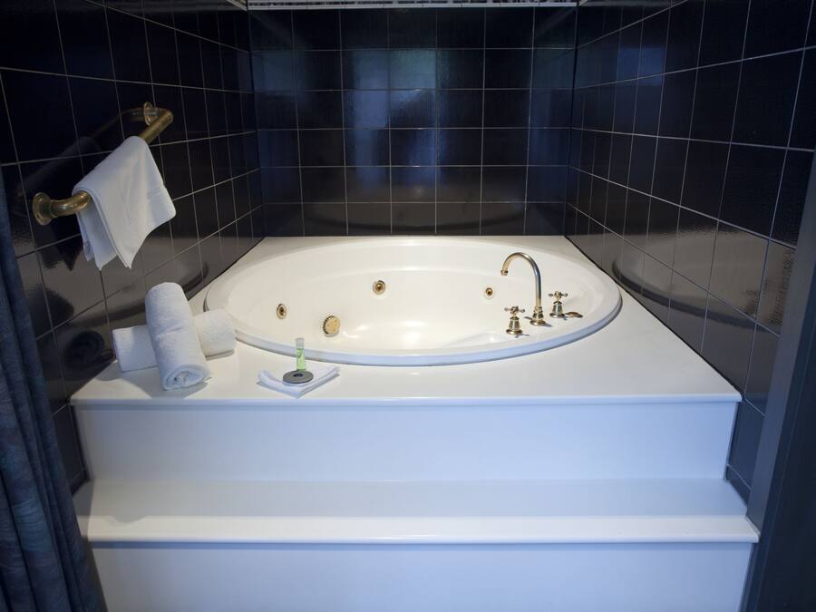 A modern bathroom with a freestanding bathtub, a towel rack, and a small shelf with toiletries.