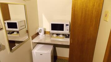 A compact hotel room with a kitchenette, including a microwave, coffee maker, and refrigerator.