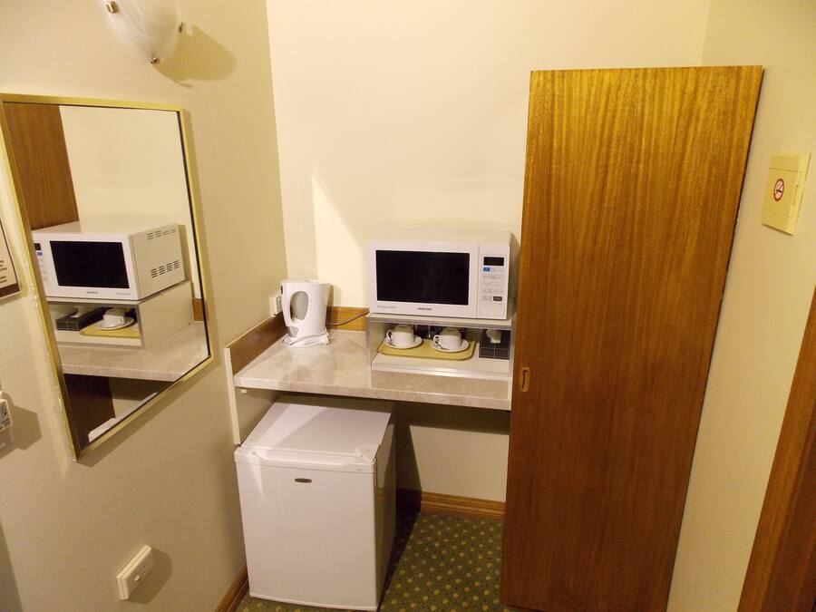 A compact hotel room with a kitchenette, including a microwave, coffee maker, and refrigerator.