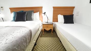 A hotel room with two beds, a nightstand, a lamp, and a patterned carpet.