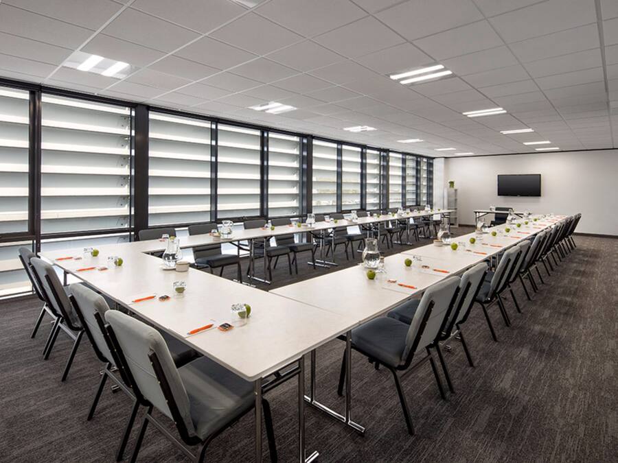 A conference room with a long table, chairs, and a TV on the wall.