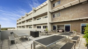 Eine Dachterrasse mit Außenmöbeln und einem Backsteingebäude im Hintergrund.