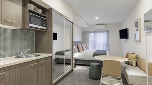 Ein modernes Hotelzimmer mit Küchenzeile, einem Bett, einer Couch und einem Essbereich.