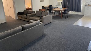 A modern living room with a sofa set, a dining table with chairs, and a kitchen area with a coffee maker. - Parkside Inn Motel (Kingsbury)