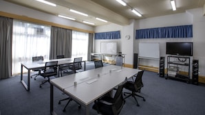 A conference room with a long table, chairs, a whiteboard, a projector, and a television. - Parkside Inn Motel (Kingsbury)