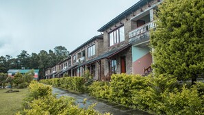 A row of traditional buildings with balconies, a stone pathway, and lush greenery. - Himalayan Deurali Resort (Pokhara)