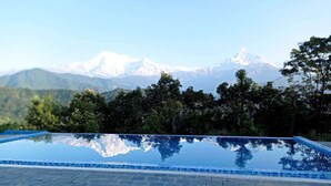 A swimming pool with a clear view of snow-capped mountains in the background. - Himalayan Deurali Resort (Pokhara)