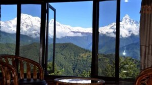 A room with large windows offering a view of snow-capped mountains and lush green hills. - Himalayan Deurali Resort (Pokhara)