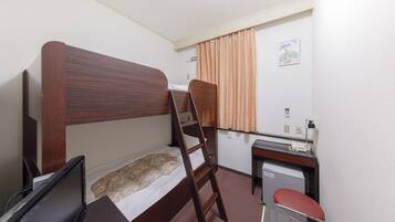 A small, single-room hotel room with a bunk bed, a desk with a telephone, a chair, and a small table.