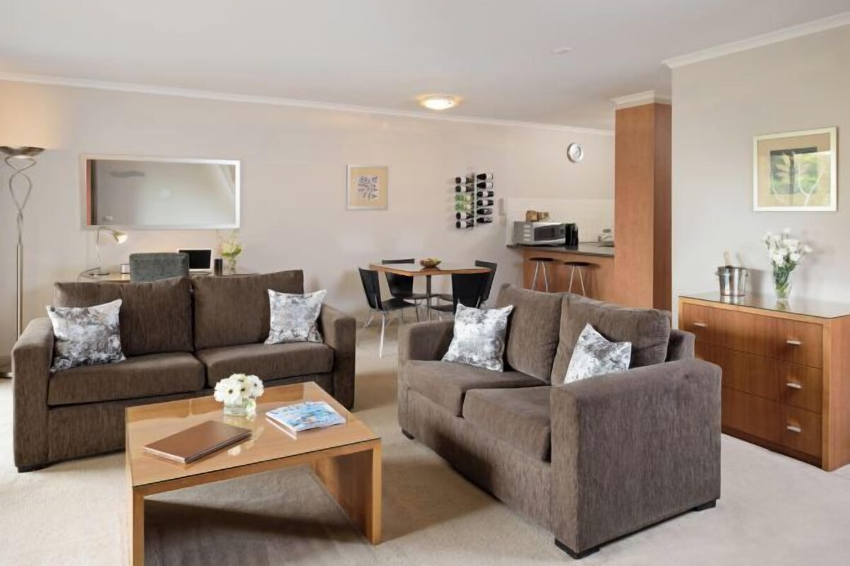 A modern living room with two sofas, a coffee table, a TV, and a dining area.