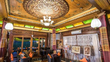 A traditional interior with ornate wooden ceiling, chandeliers, and wicker furniture.