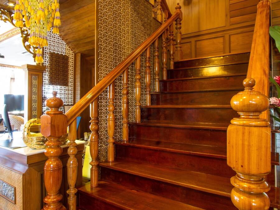 Una escalera de madera con una escultura decorativa de cabeza de elefante, un candelabro y un papel tapiz estampado.