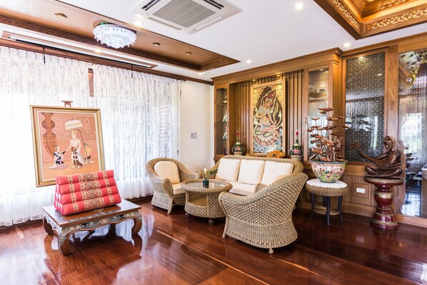 Una habitación tradicional con muebles de mimbre, un sofá, una mesita pequeña y una estatua decorativa de Buda.