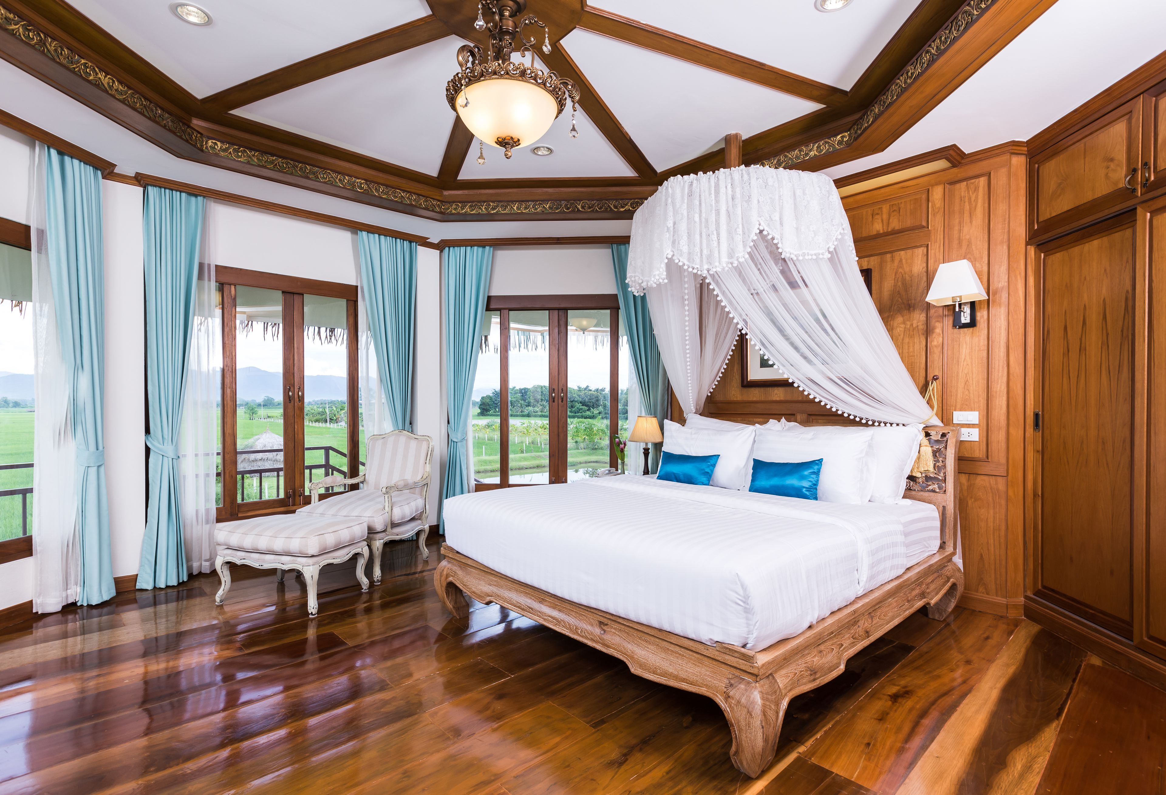 Une chambre spacieuse avec un grand lit, un baldaquin et une vue sur l’extérieur.