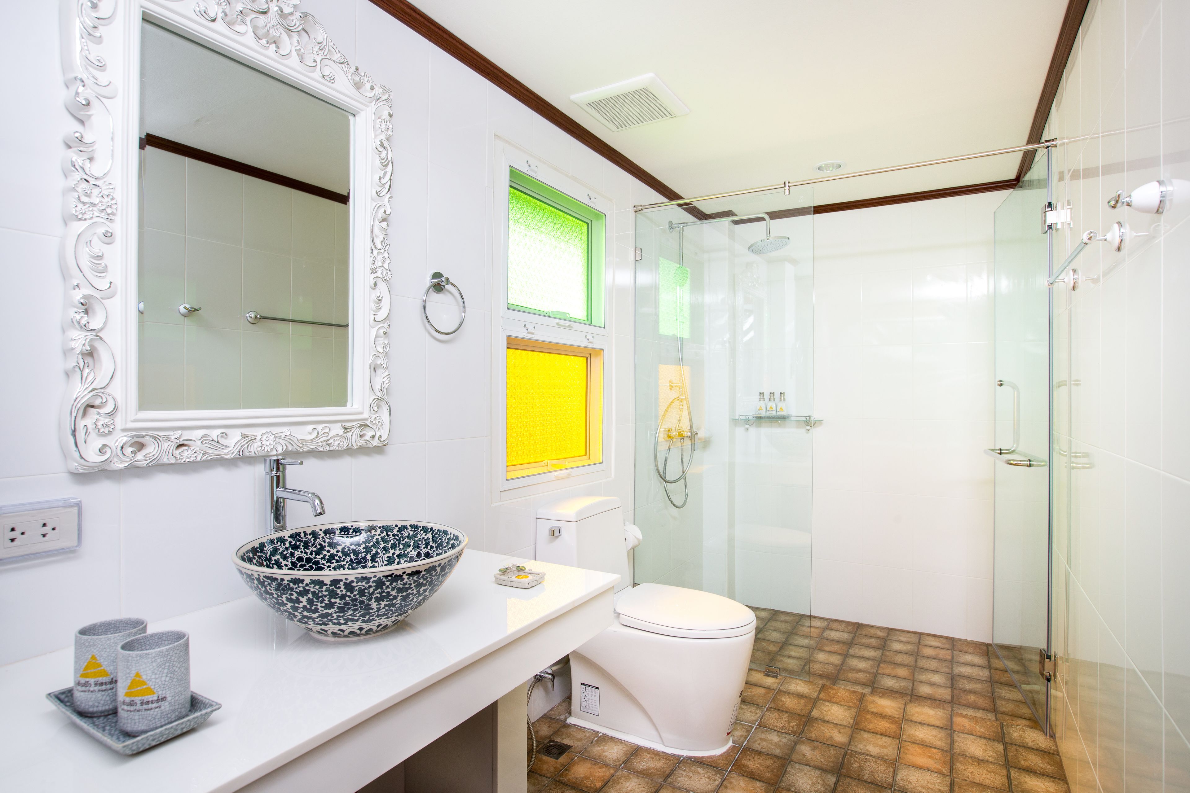 A modern bathroom with a white sink, a large mirror, a glass-enclosed shower, and a toilet.