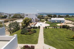 A coastal property with a well-maintained lawn, a stone pathway, and a view of the sea. - Dolphin Kastraki Studios (Naxos)