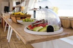 A buffet table with a variety of fruits and a water dispenser. - Dolphin Kastraki Studios (Naxos)