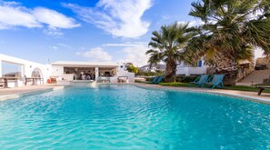 A swimming pool with lounge chairs and a covered seating area. - Dolphin Kastraki Studios (Naxos)