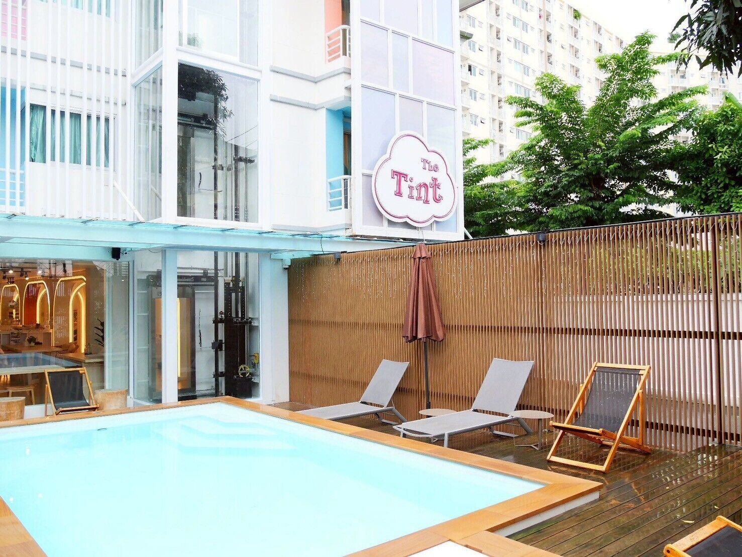 A swimming pool area with lounge chairs and a sign that reads "The Tint".