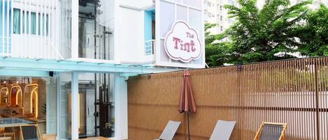 A swimming pool area with lounge chairs and a sign that reads "The Tint".