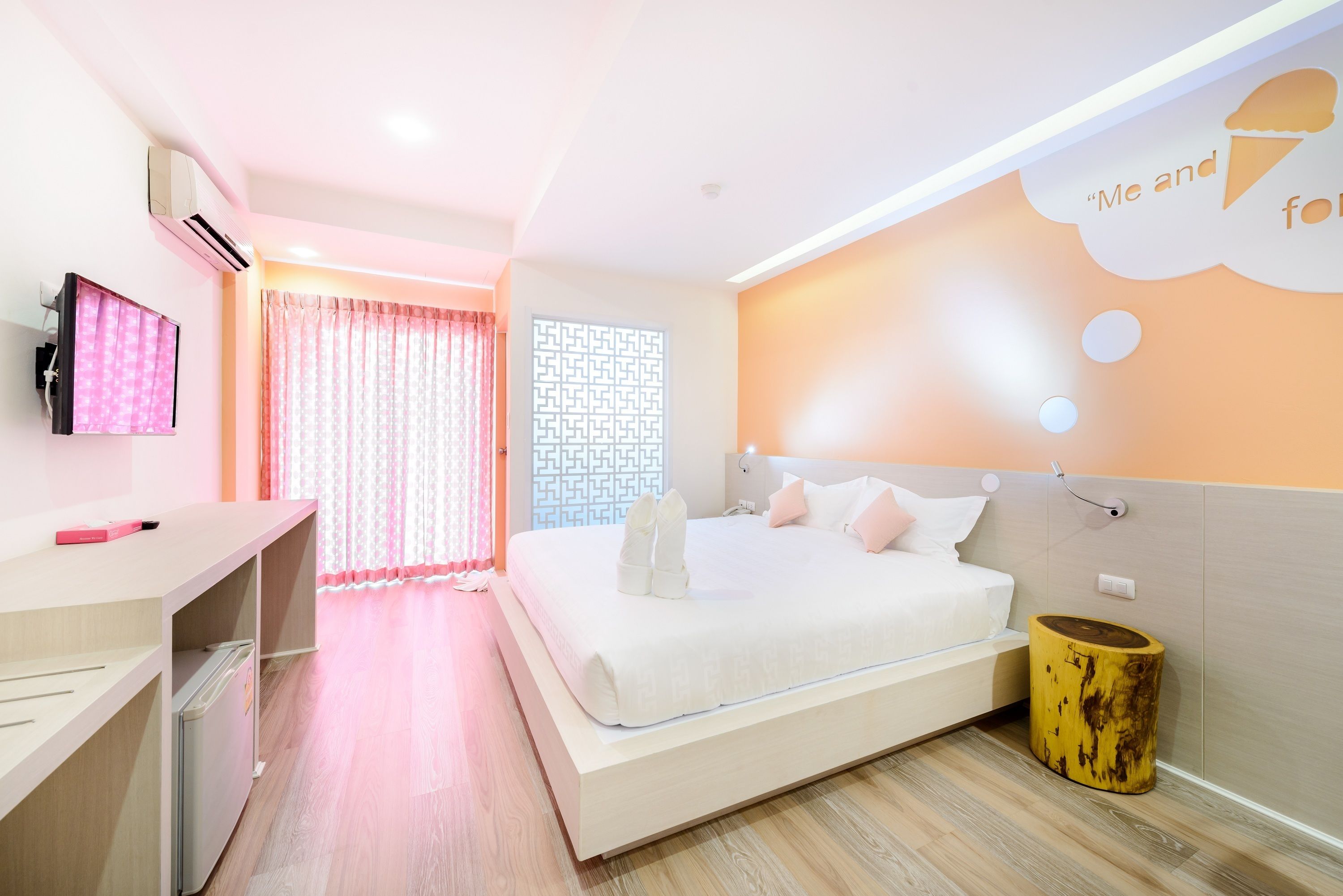A modern hotel room with a bed, a desk, a TV, and a decorative wall.