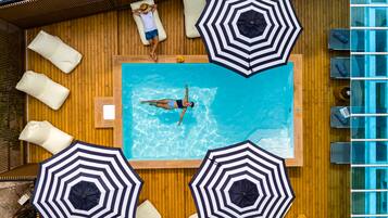 A swimming pool with lounge chairs and umbrellas, surrounded by wooden decking.