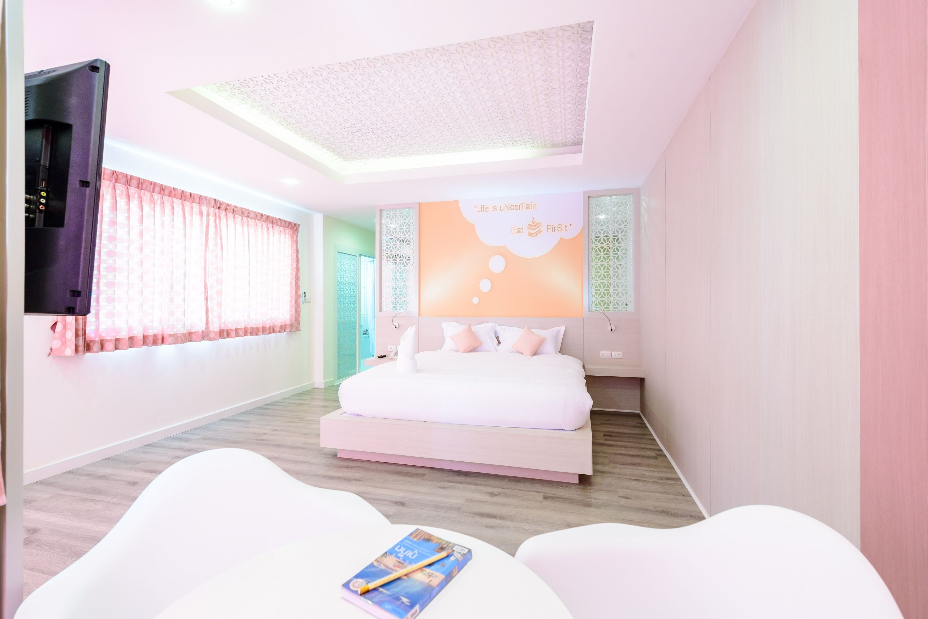 A modern bedroom with a bed, a TV, and a poster on the wall.