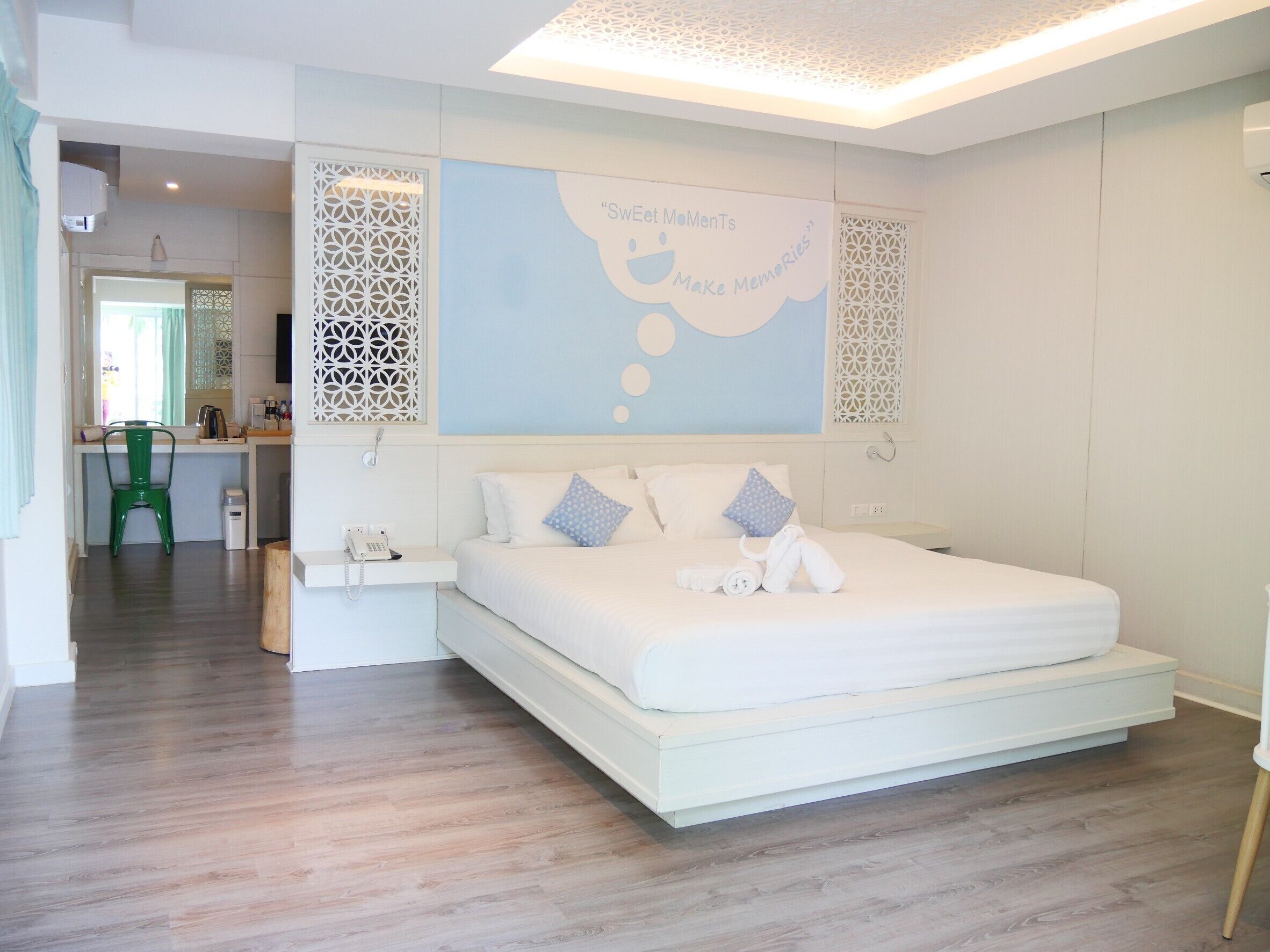 Quarto moderno com cama grande, mesa de cabeceira e parede decorativa com luminária.