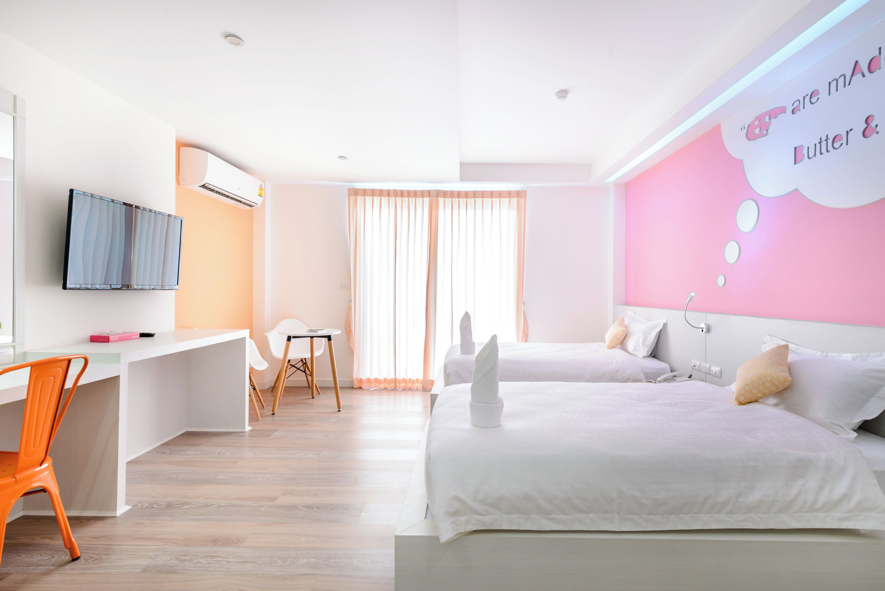 Een hotelkamer met twee bedden, een bureau, een stoel en een televisie.