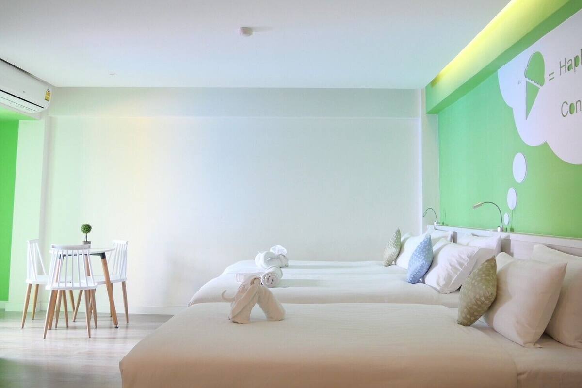 Una habitación de hotel moderna con una cama, una pequeña mesa con sillas y una pared de acento verde.