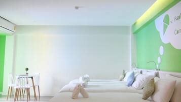A modern hotel room with a bed, a small table with chairs, and a green accent wall.