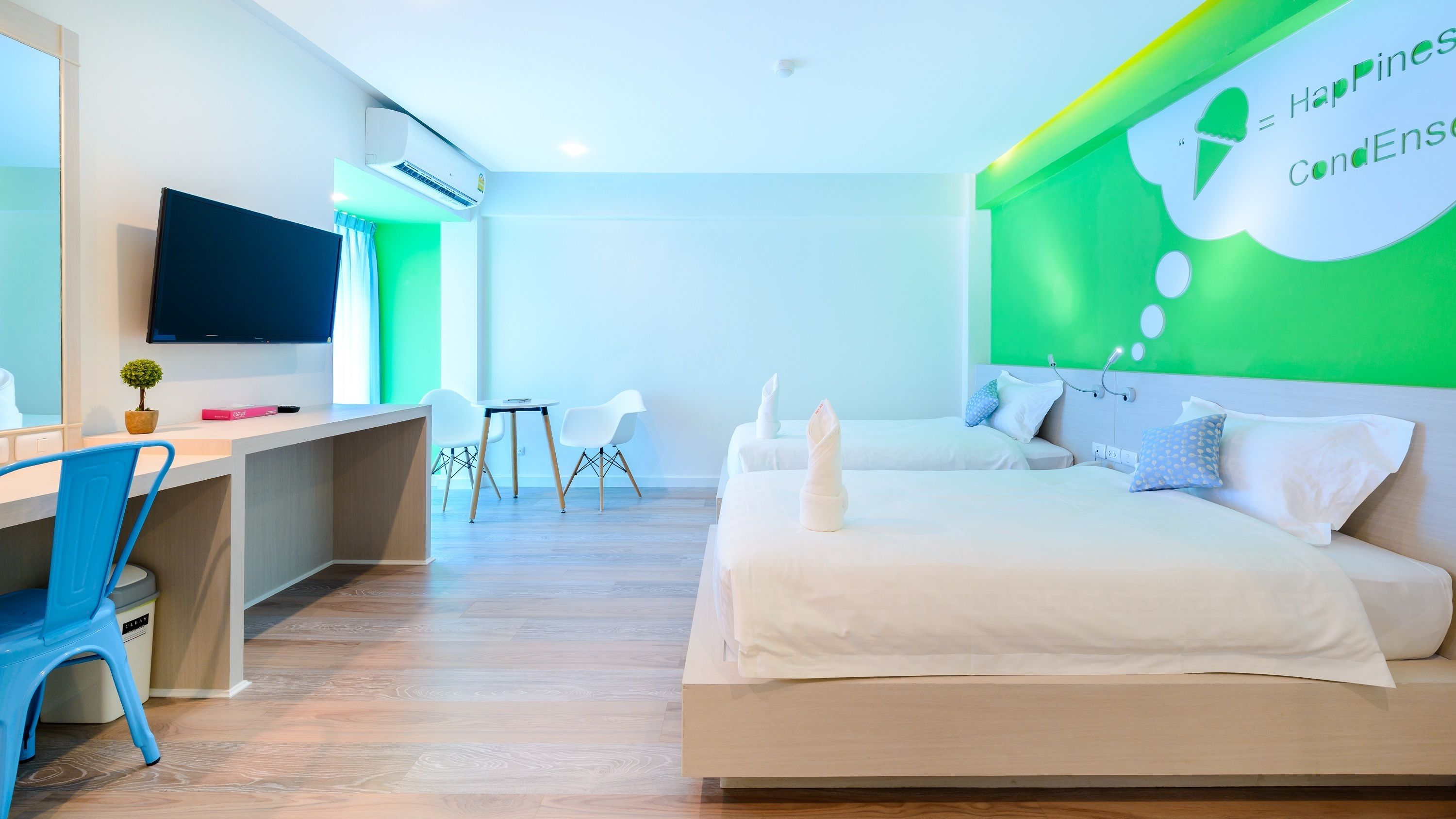 A modern hotel room with a bed, desk, and chairs.