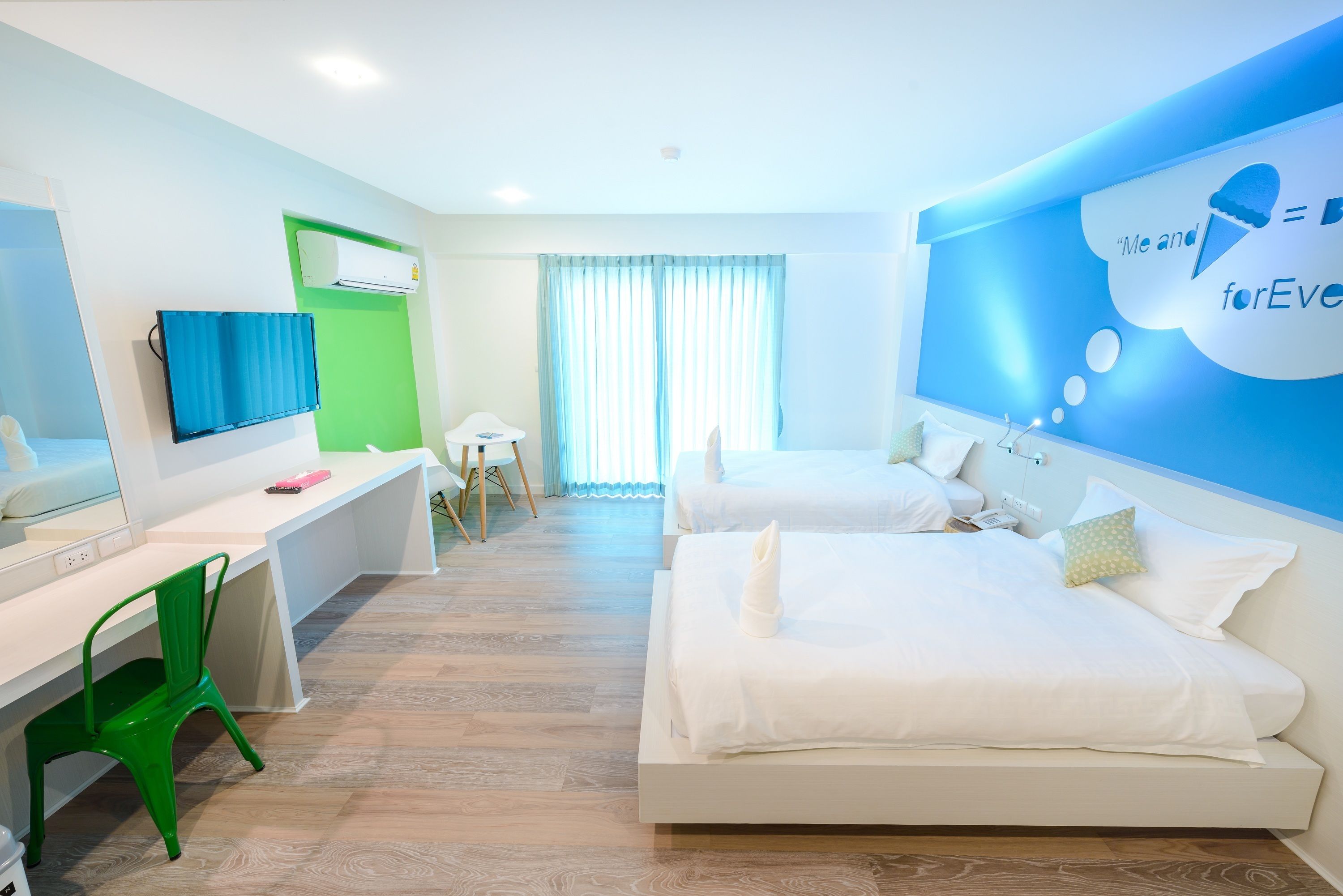 Une chambre d’hôtel moderne équipée de deux lits, d’un bureau, d’une chaise et d’un téléviseur.