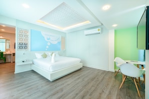 Moderni hotellihuone, jossa on sänky, työpöytä ja tuoli.