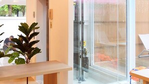 Un interior moderno con un gran ventanal que da a un espacio exterior, una mesa de madera y una planta.