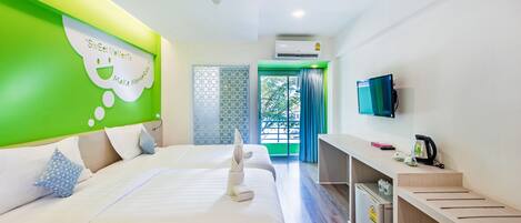 A hotel room with two beds, a TV, a desk, and a view of the outdoors.